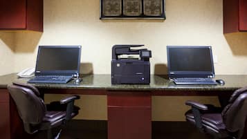 A conference room with two desks, each with a laptop, a printer, and a telephone.