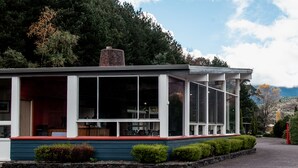 A modern building with large windows and a red roof, surrounded by greenery. - Silver Hills Motel (Queenstown)