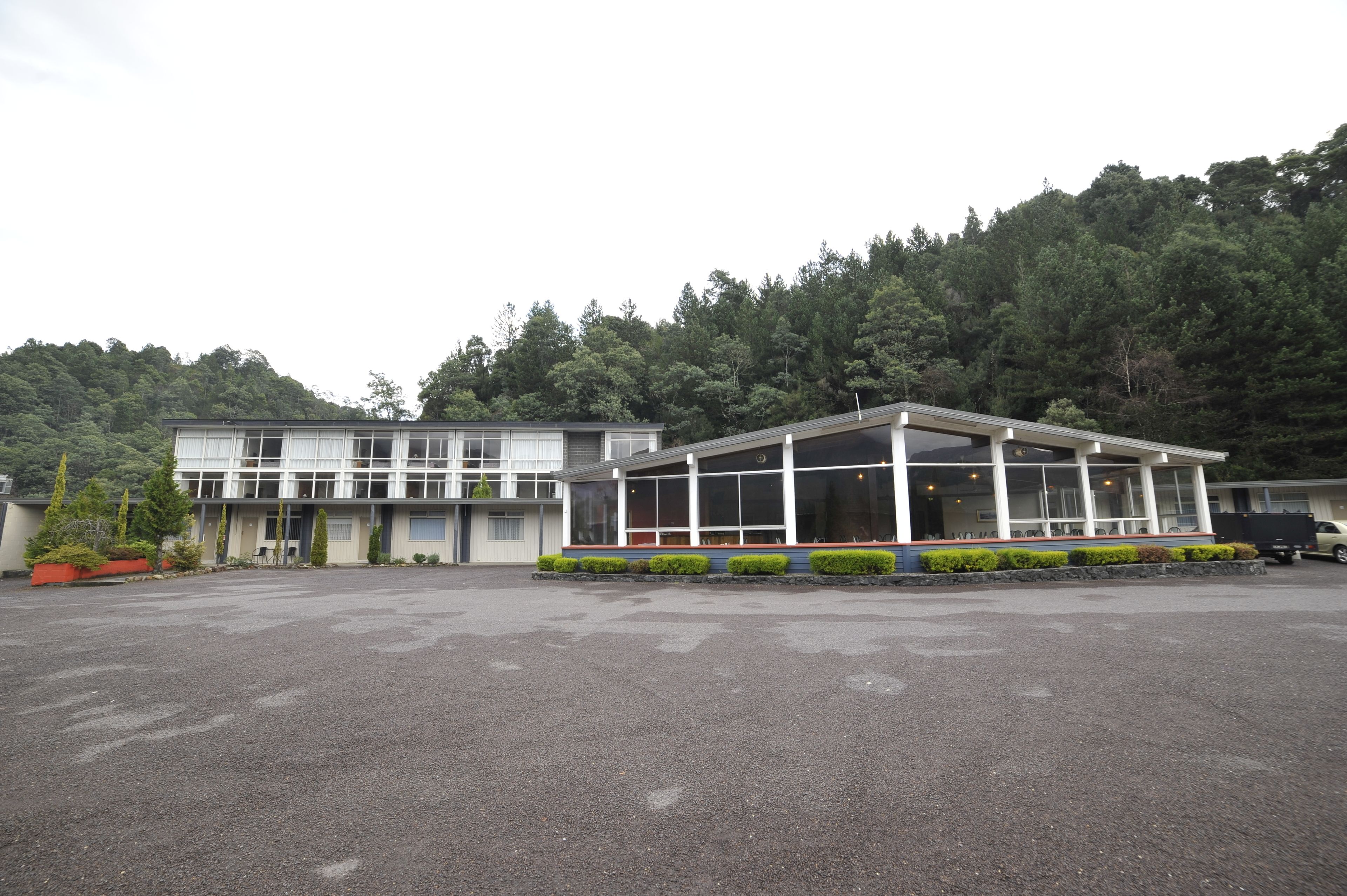 A building with a large glass facade, a covered outdoor area, and a parking lot.