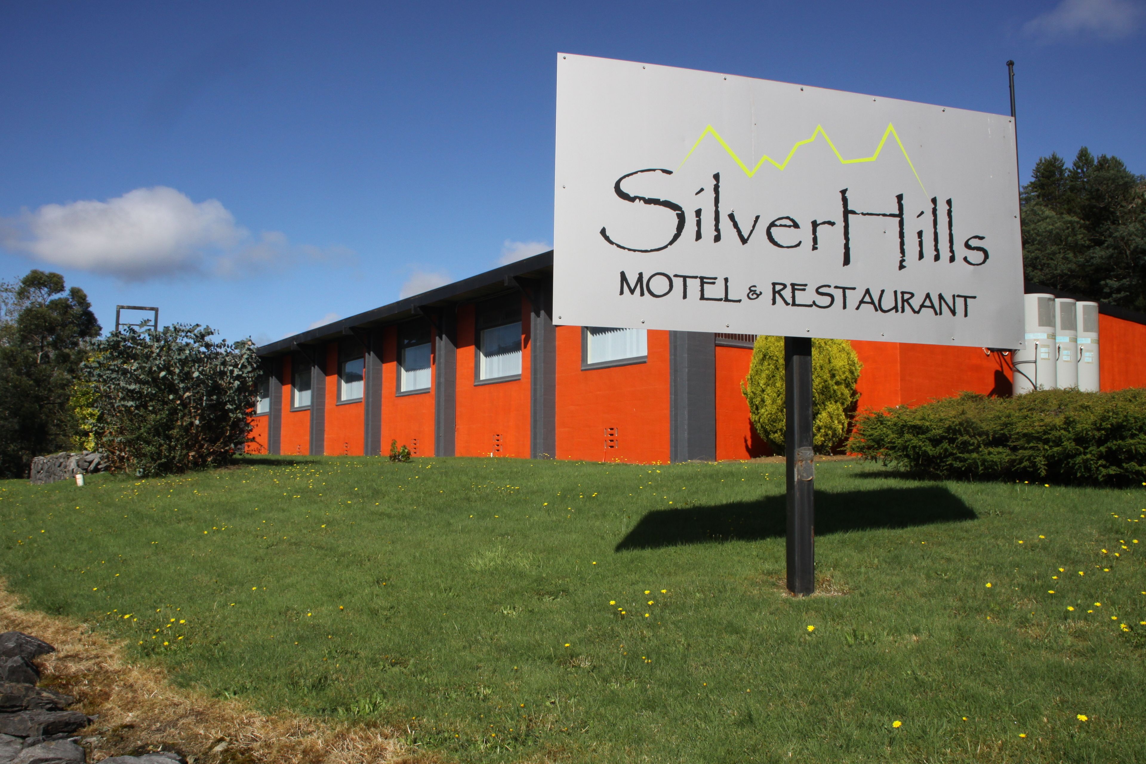Une enseigne indiquant le « Silver Hills Motel & Restaurant », avec un bâtiment moderne en arrière-plan.