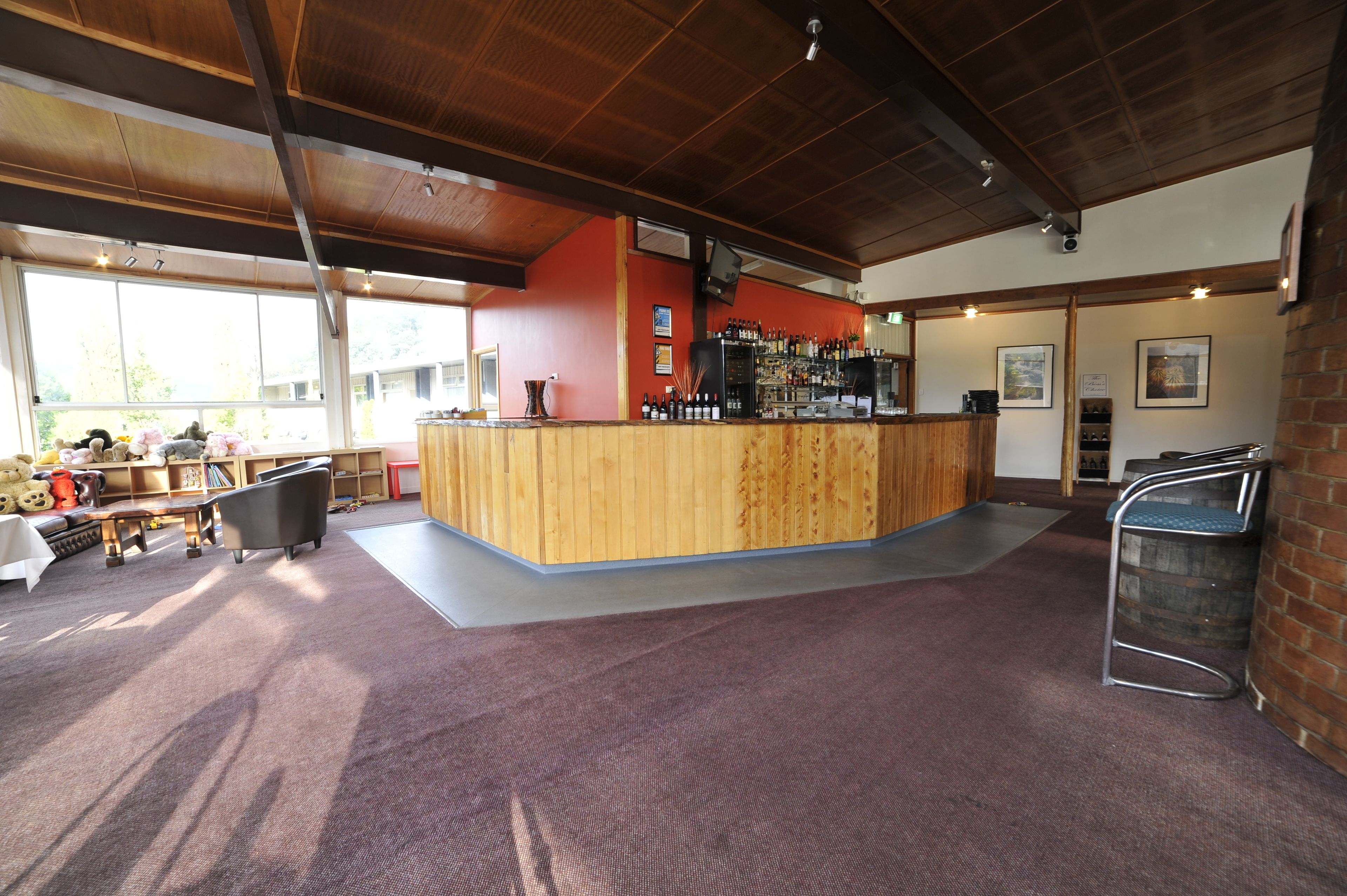 A bar area with a wooden counter, seating, and a view of the outdoors.