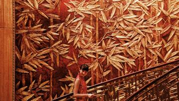 A person standing on a staircase with a large wall mural of bamboo leaves.