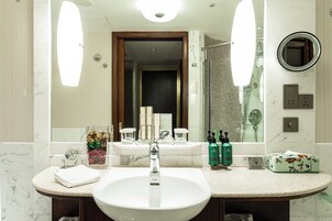 A bathroom with a large mirror, a sink, and a shower area.