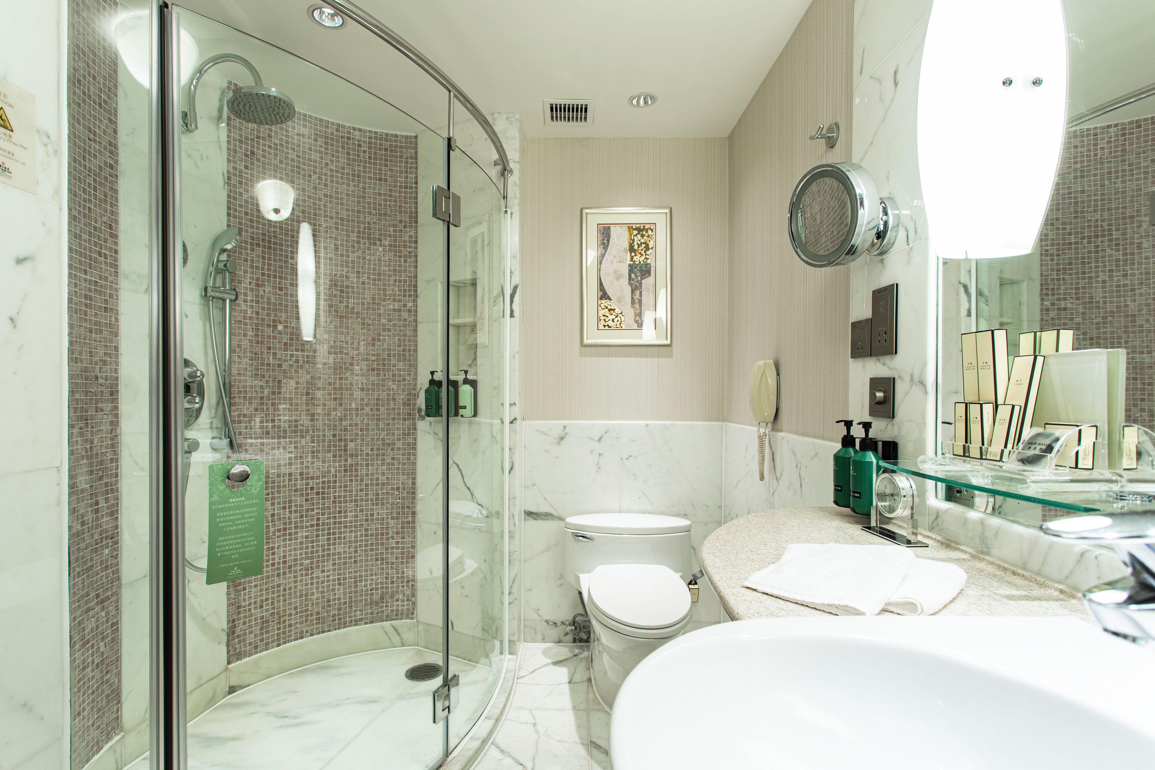 A modern bathroom with a glass-enclosed shower, a toilet, and a sink with a glass countertop.