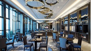 Eine moderne Hotelhalle mit Bar, Sitzgelegenheiten und großen Fenstern.