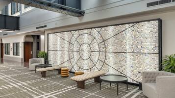 Um hall de entrada com piso estampado, disposição de assentos e parede decorativa com design geométrico.