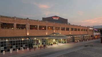 En byggnad i tegel med en skylt som visar texten ”Lucas Oil Stadium” och en överbyggd entré med krukväxter.
