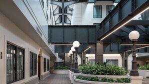 A spacious indoor corridor with a high ceiling, featuring a central staircase, multiple windows, and modern lighting fixtures. - Crowne Plaza Indianapolis-Dwtn-Union Stn by IHG (Indianapolis)