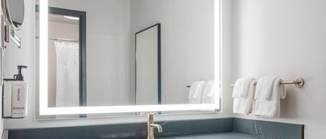 Un baño moderno con un espejo grande, un lavamanos y un perchero para toallas.