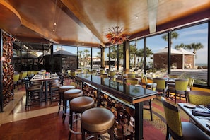A restaurant with a bar area, outdoor seating, and a view of the beach.