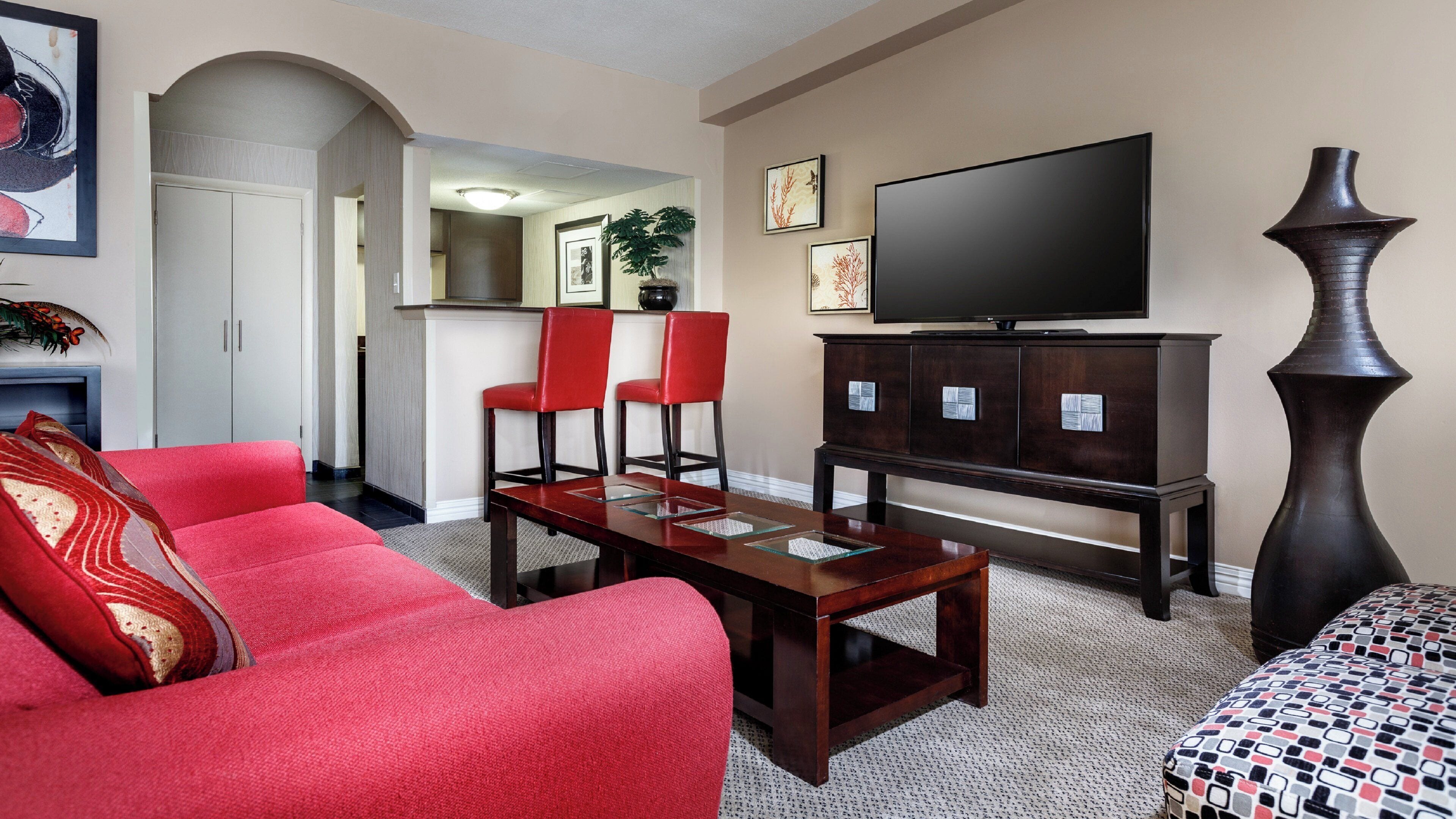 A living room with a red sofa, a coffee table, a TV, and a cabinet.