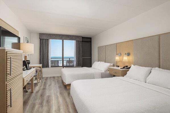 A hotel room with two beds, a desk, a chair, a lamp, a phone, and a view of the sea. - Holiday Inn Resort: Galveston-On The Beach by IHG (Galveston)