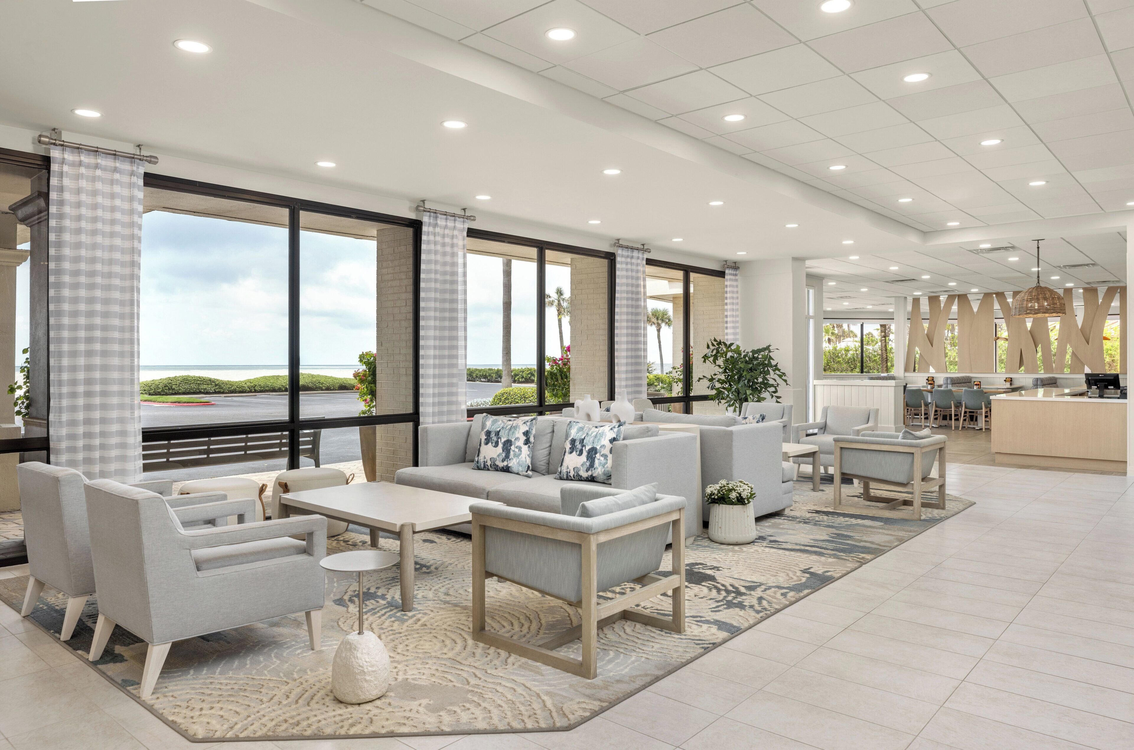 A spacious lobby with a large seating area, a bar, and a view of the outdoors.