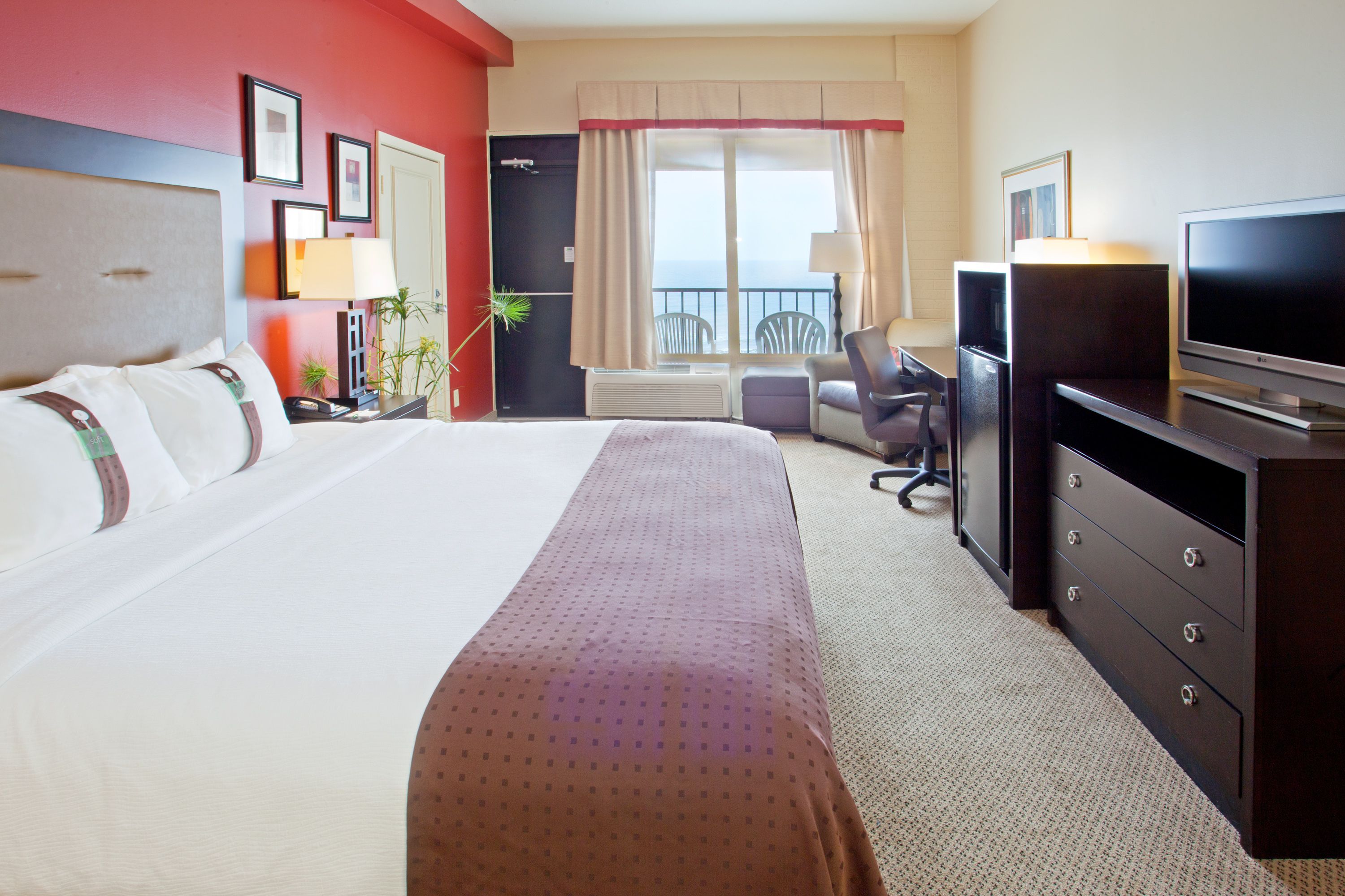 Une chambre d’hôtel avec un grand lit, un bureau avec une télévision, une chaise et une fenêtre donnant sur un beau paysage.