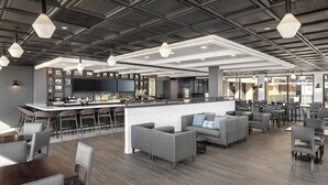 Uma área de bar moderna com balcão, assentos e uma tela grande.