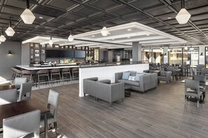 A modern bar area with a counter, seating, and a large screen. - Holiday Inn Resort: Galveston-On The Beach by IHG (Galveston)