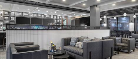 A modern lounge area with a bar, seating, and framed pictures on the walls.