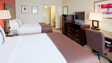 Una habitación de hotel con dos camas, televisión, escritorio y una silla.