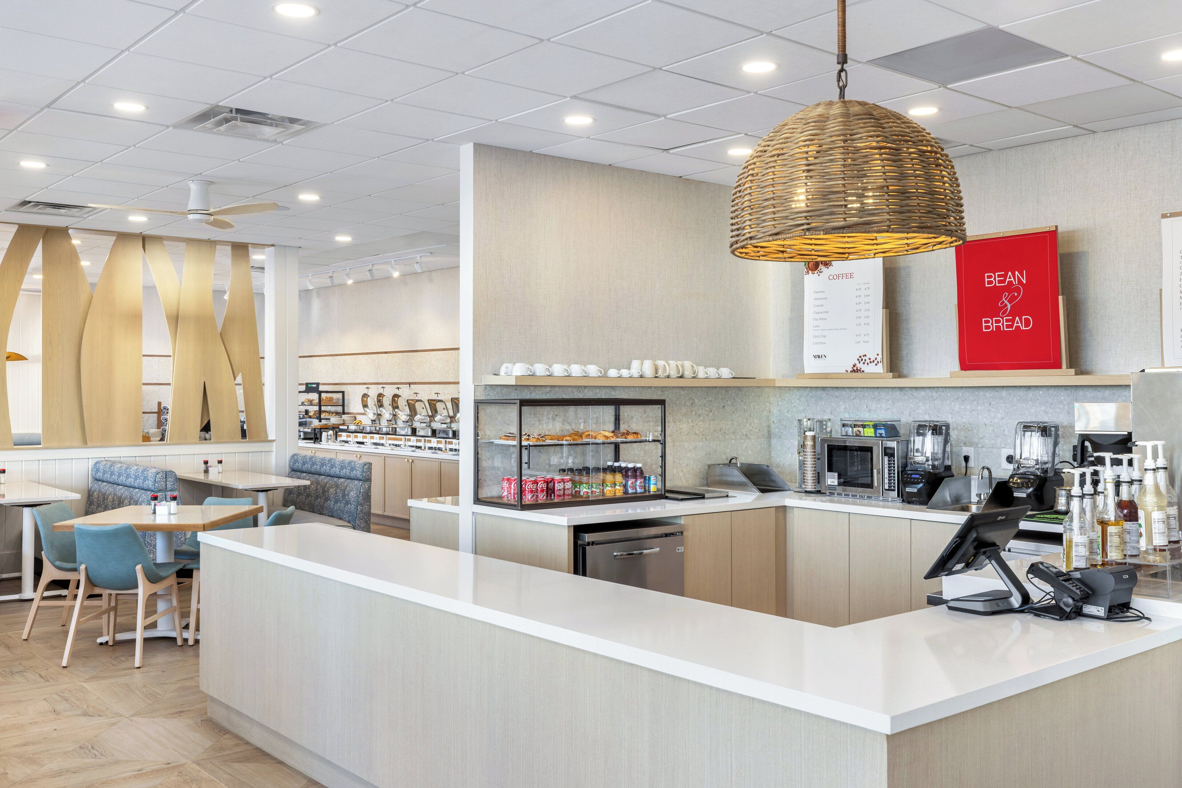 A modern cafe with a central counter, seating area, and a menu board.