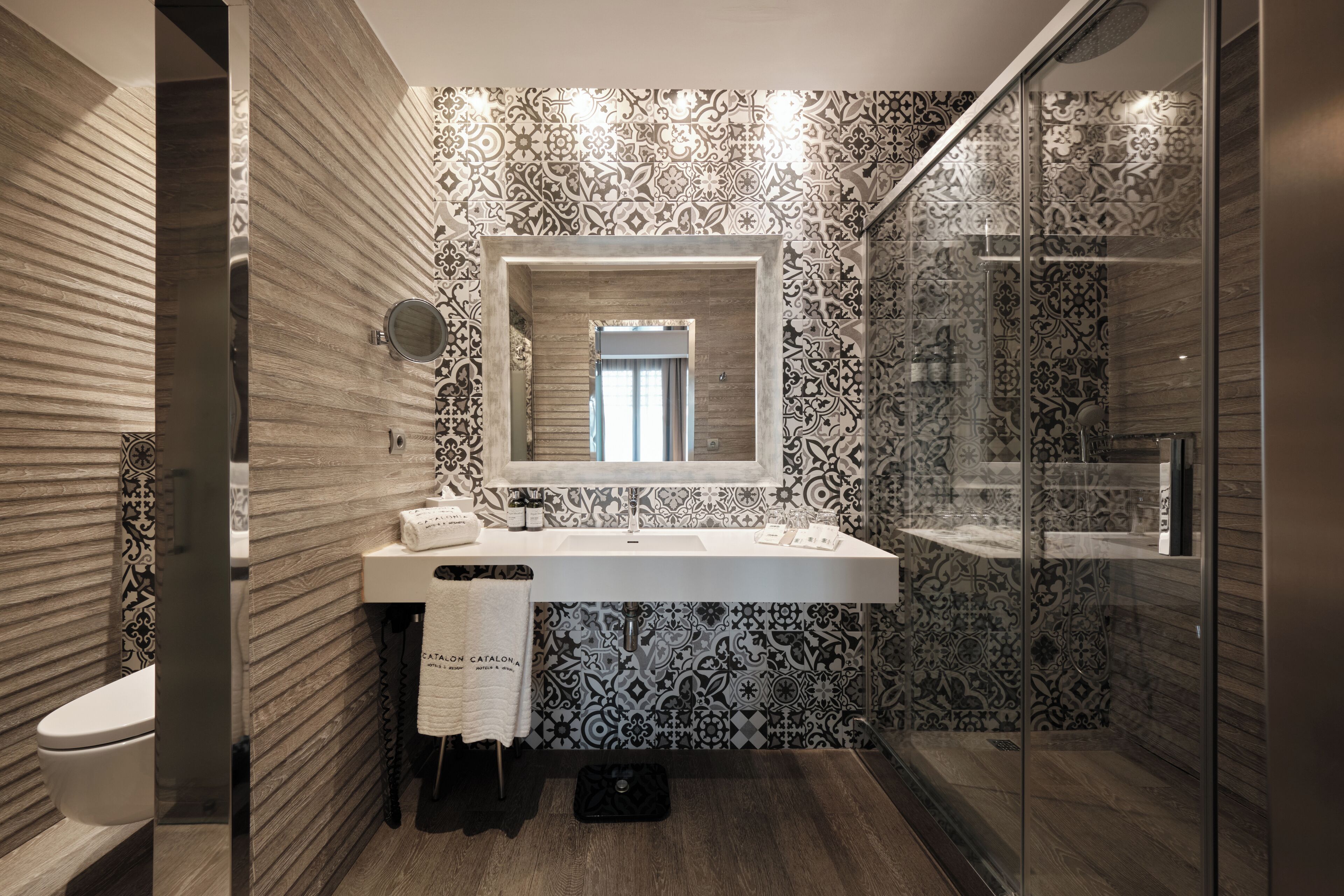 Un baño moderno con un espejo grande, un lavamanos y una zona de ducha.