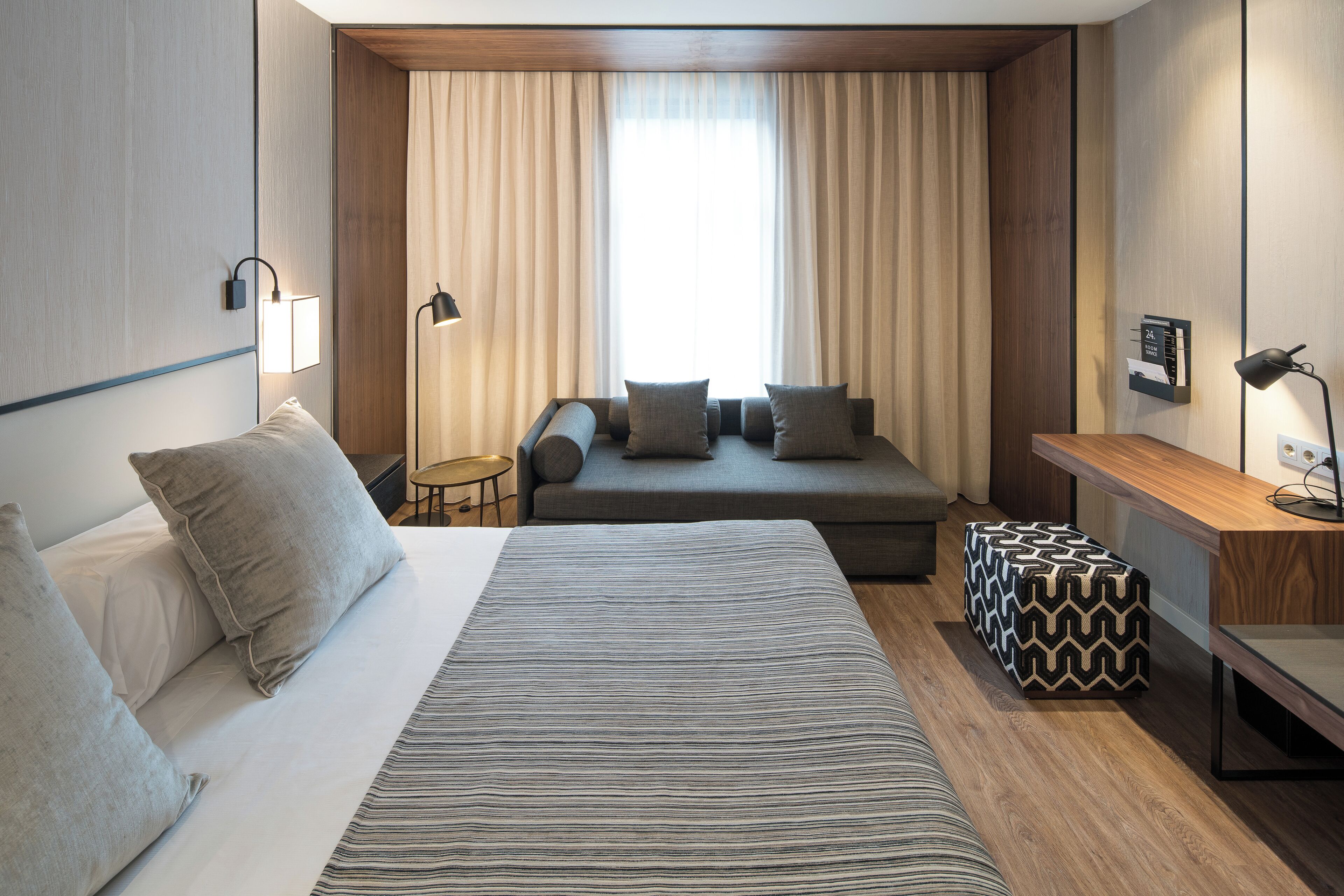 Una habitación de hotel moderna con una cama grande, un sofá, una mesita y un escritorio.