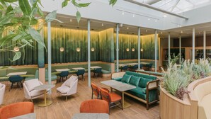 Un espace de détente intérieur moderne, avec des chaises, des tables et un canapé verts et oranges.