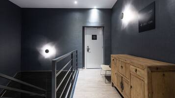 Un pasillo moderno con un armario de madera, una escalera y señalización en la pared.