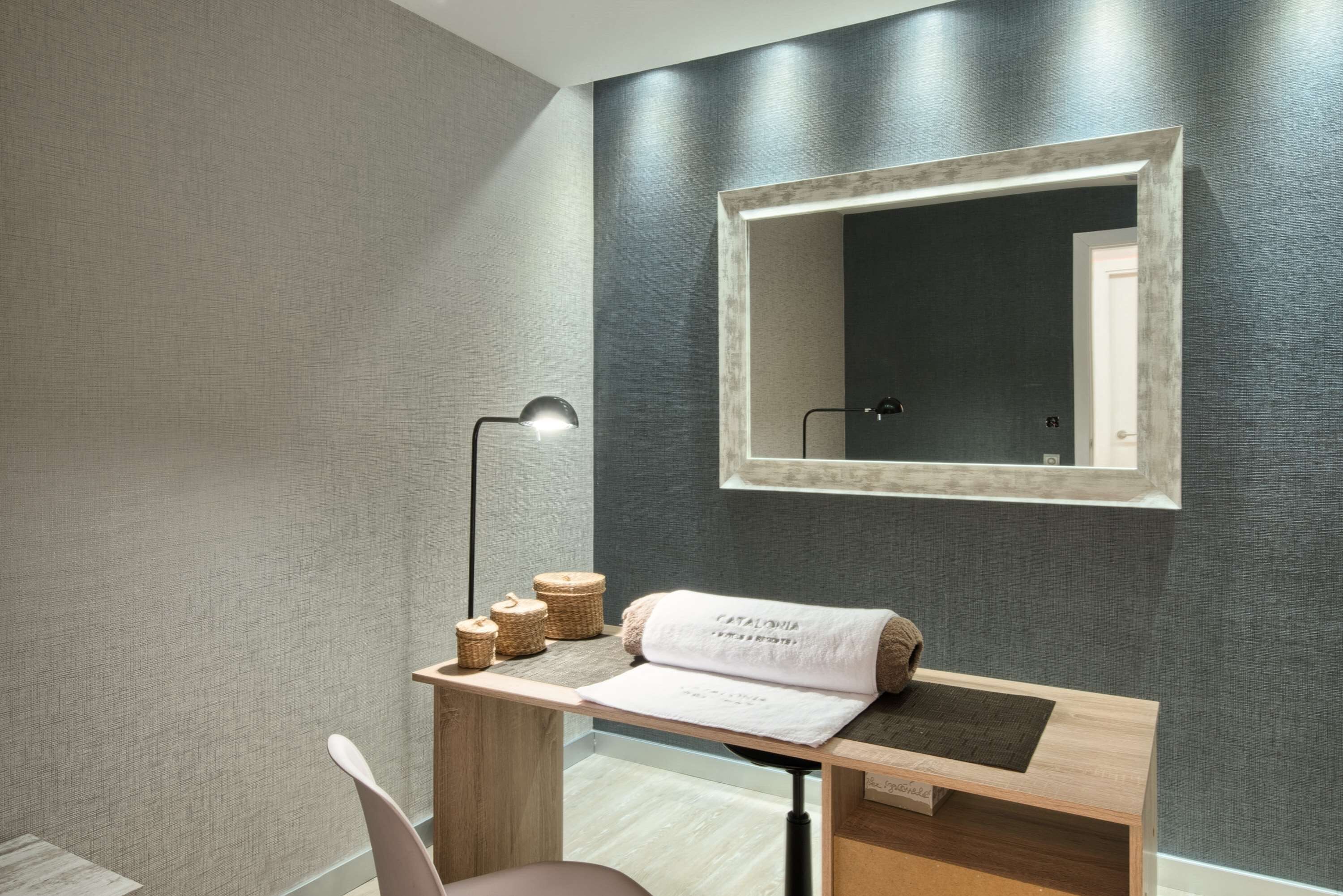Un baño moderno con tocador de madera, un espejo, una toalla y una lámpara de pie.