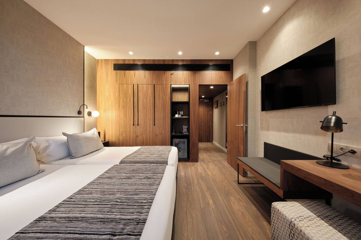 Une chambre d’hôtel moderne équipée d’un grand lit, d’un bureau, d’une télévision et d’une armoire.