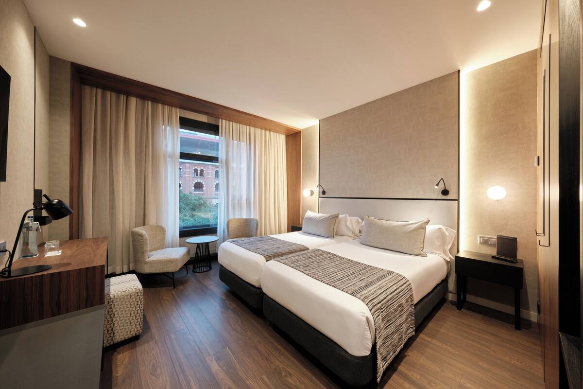 Une chambre d’hôtel moderne équipée d’un grand lit, d’un bureau, d’une chaise et d’une petite table.
