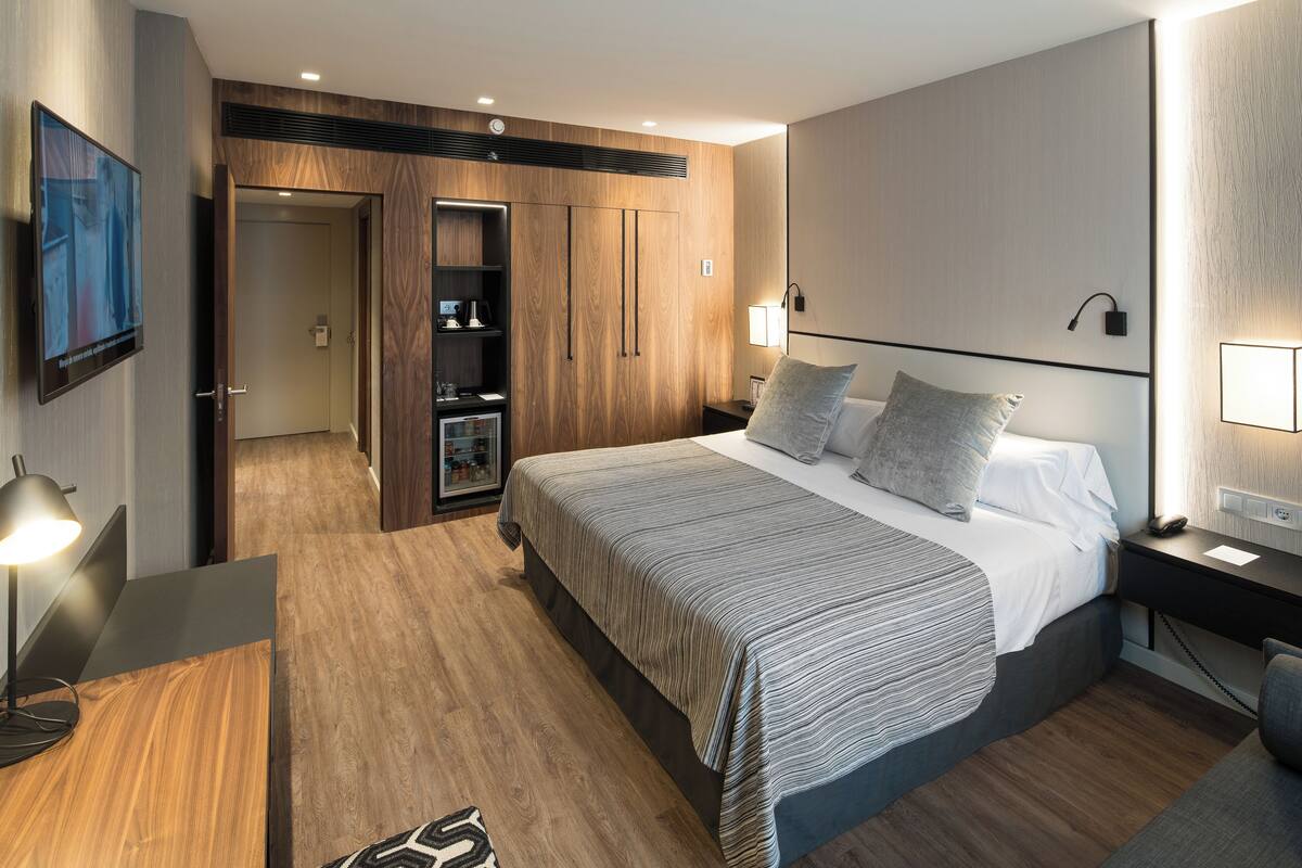Une chambre d’hôtel moderne, dotée d’un grand lit, de tables de chevet, d’une télévision et d’une armoire.
