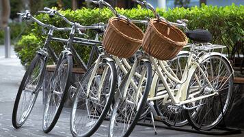 Varias bicicletas estacionadas en una acera, con cestas en el manillar.
