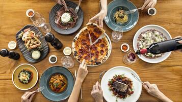 A group of people dining around a wooden table with various dishes.
