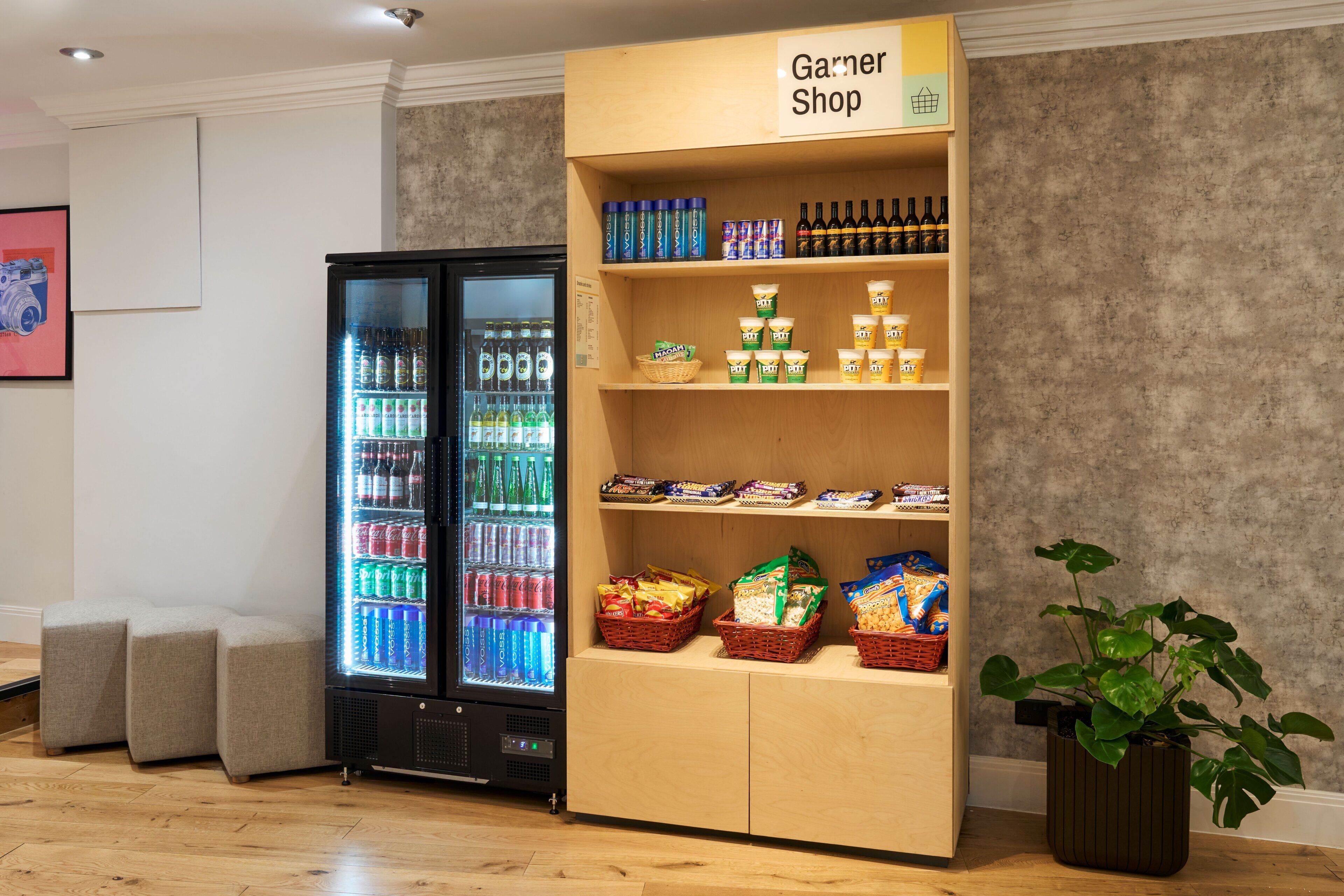 A retail area with a refrigerated display and shelves stocked with snacks and beverages.
