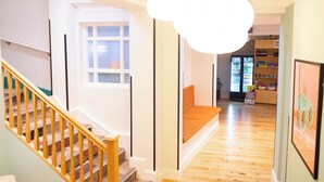 Un escalier avec des rampes en bois menant à un palier où se trouve un banc.