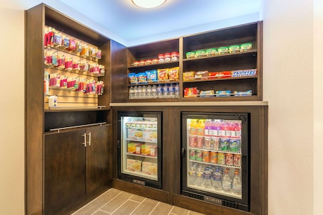 A snack and beverage vending area with multiple shelves stocked with snacks, drinks, and bottled water.