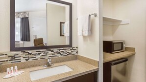 A bathroom with a sink, mirror, microwave, and towel rack. - Ramada by Wyndham Monterey (Monterey)