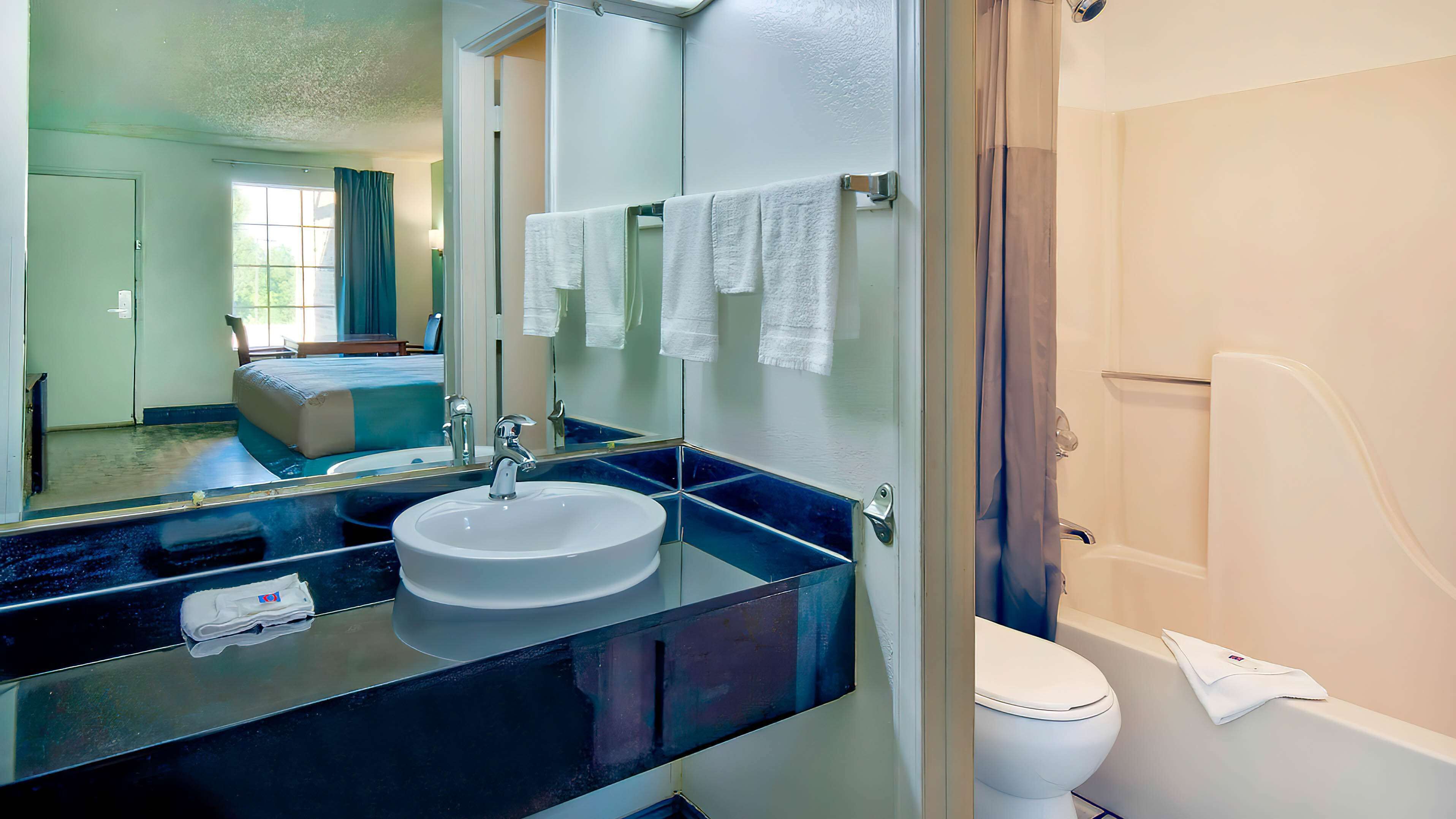 Een moderne badkamer met een grote spiegel, een wastafel en een toilet.