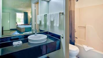 Un baño moderno con un espejo grande, un lavabo y un inodoro.