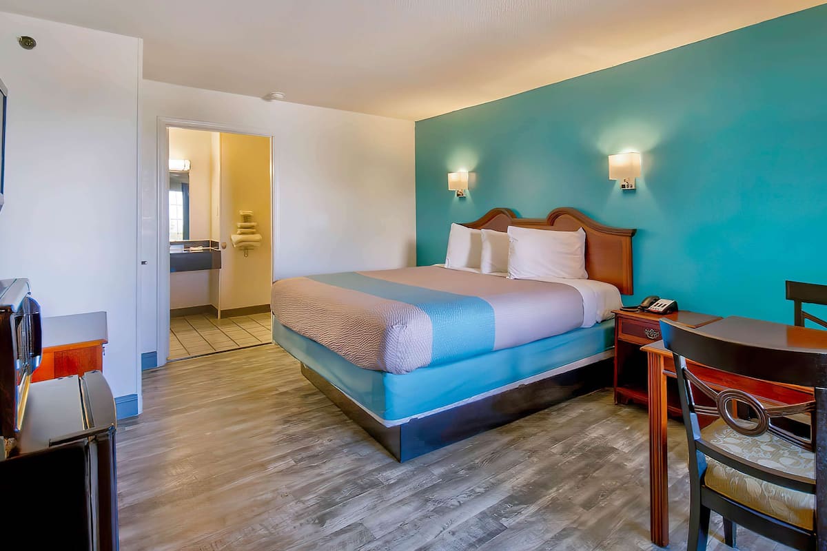 Une chambre d’hôtel équipée d’un lit, d’une table de chevet, d’une chaise et d’un bureau avec un téléphone.