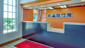 A reception area with a red carpet, orange walls, and framed pictures on the wall.