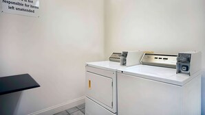 A small, clean room with a white washing machine, a dryer, and a metal filing cabinet.