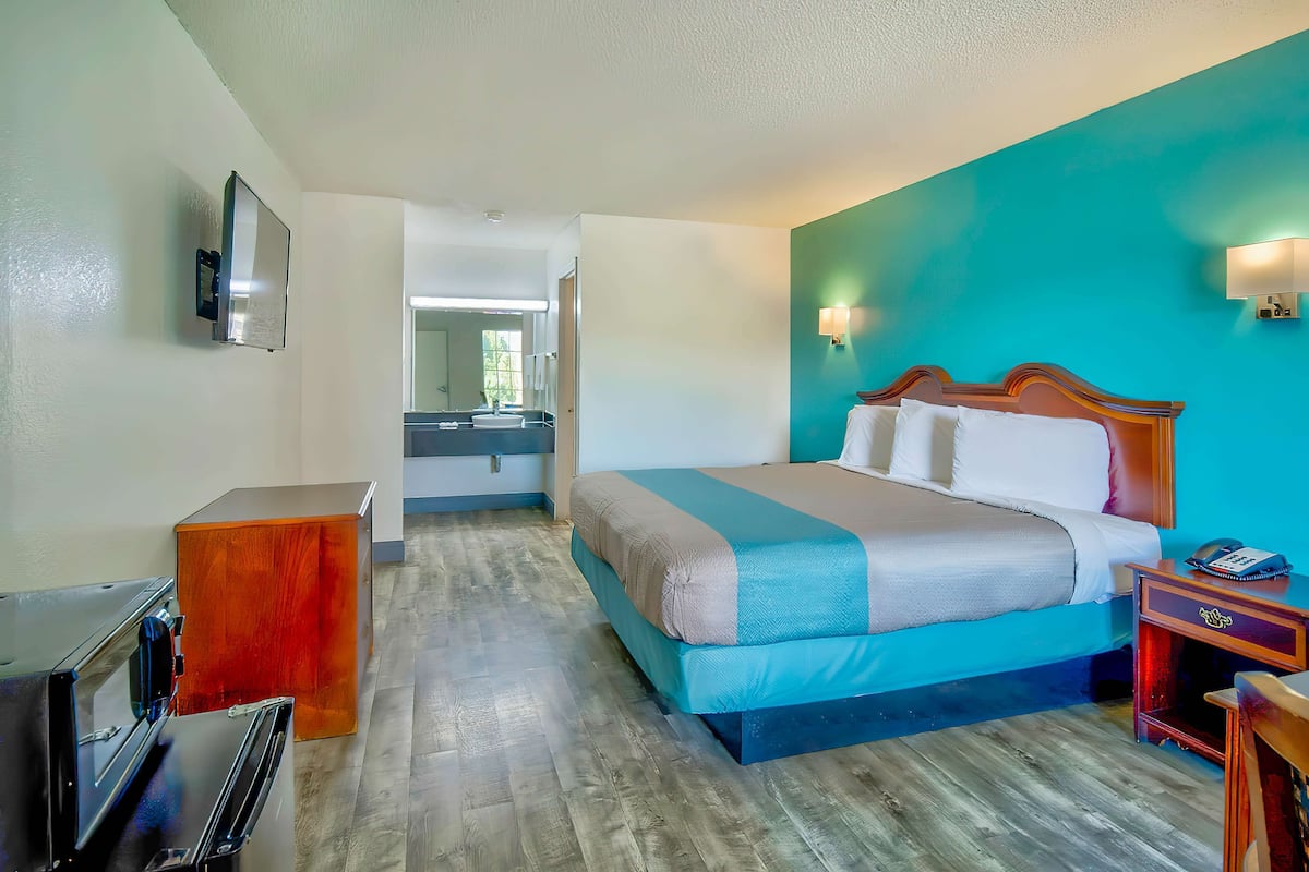 Une chambre d’hôtel avec un lit, un bureau, un miroir et une télévision.