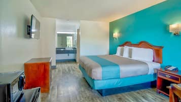 A hotel room with a bed, a desk, a mirror, and a TV.