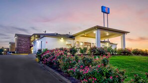 Un motel con fachada de ladrillo, una zona de estacionamiento techada y un letrero que indica que es un Motel 6.