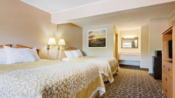 A hotel room with two beds, a bathroom with a mirror, and a TV.