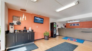 Un vestíbulo moderno de hotel con una máquina de café, un televisor y un expendedor.