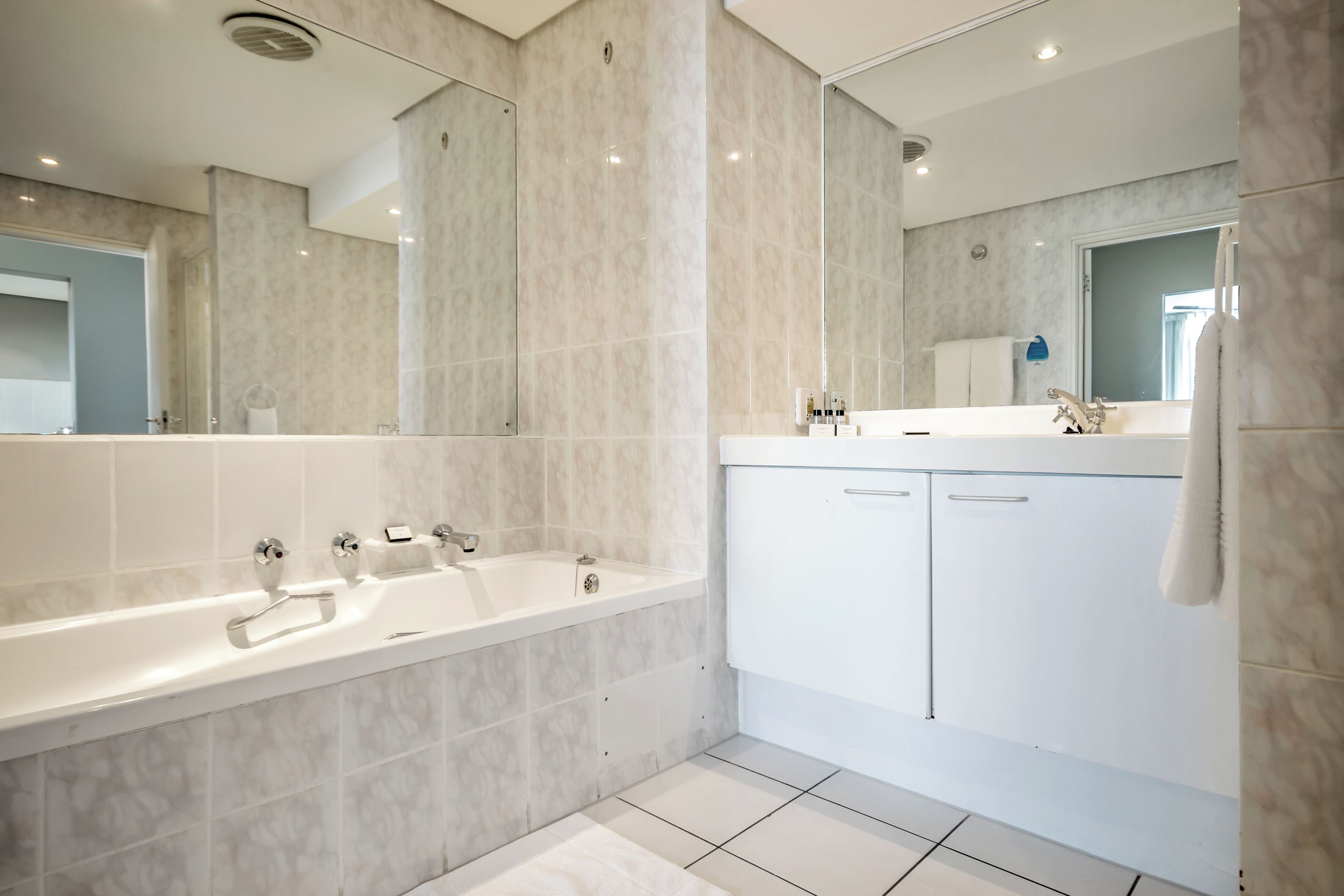 Ein modernes Badezimmer mit einer großen Badewanne, einem Waschbecken und einem Spiegel.