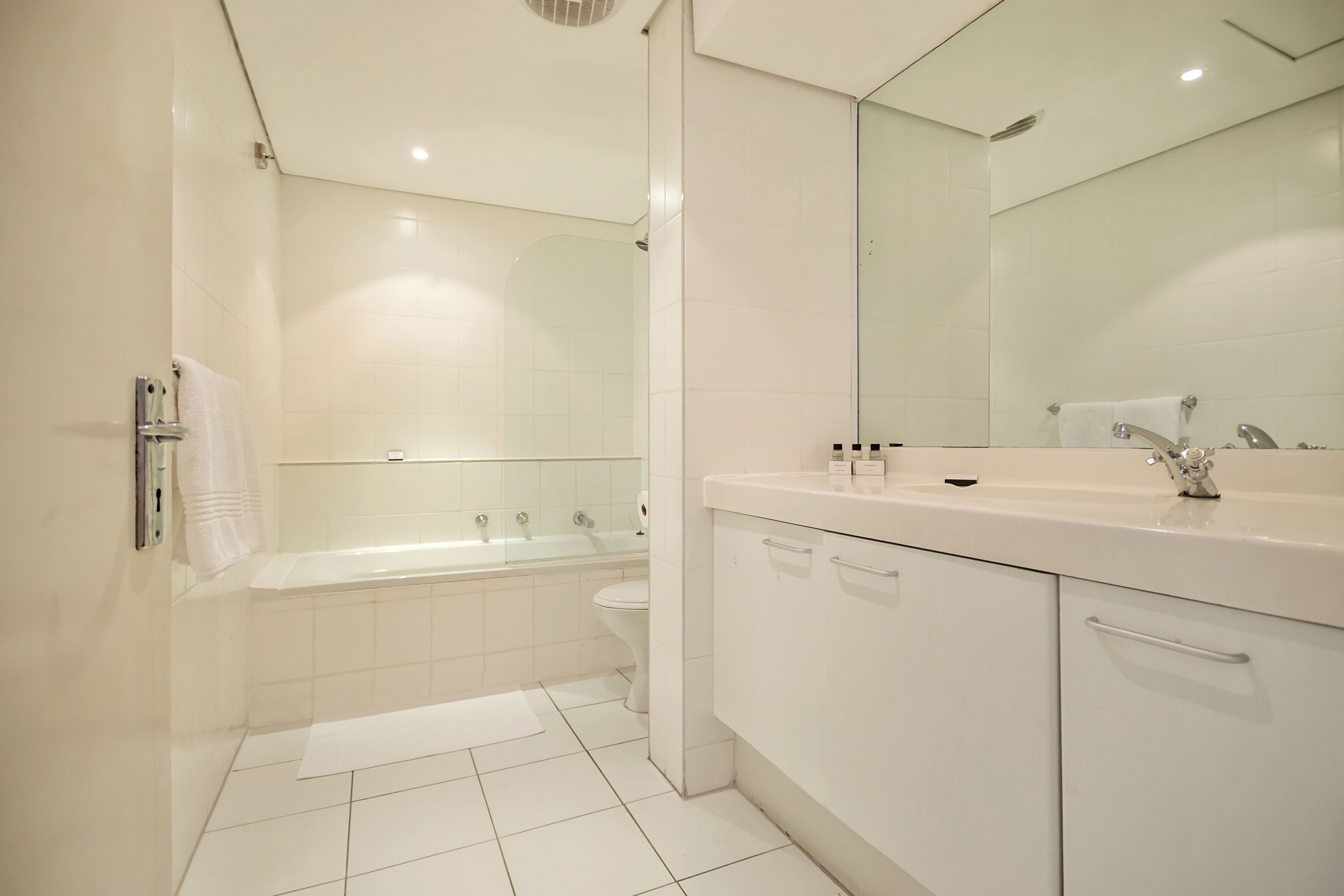 A modern bathroom with a bathtub, toilet, and vanity with a mirror.