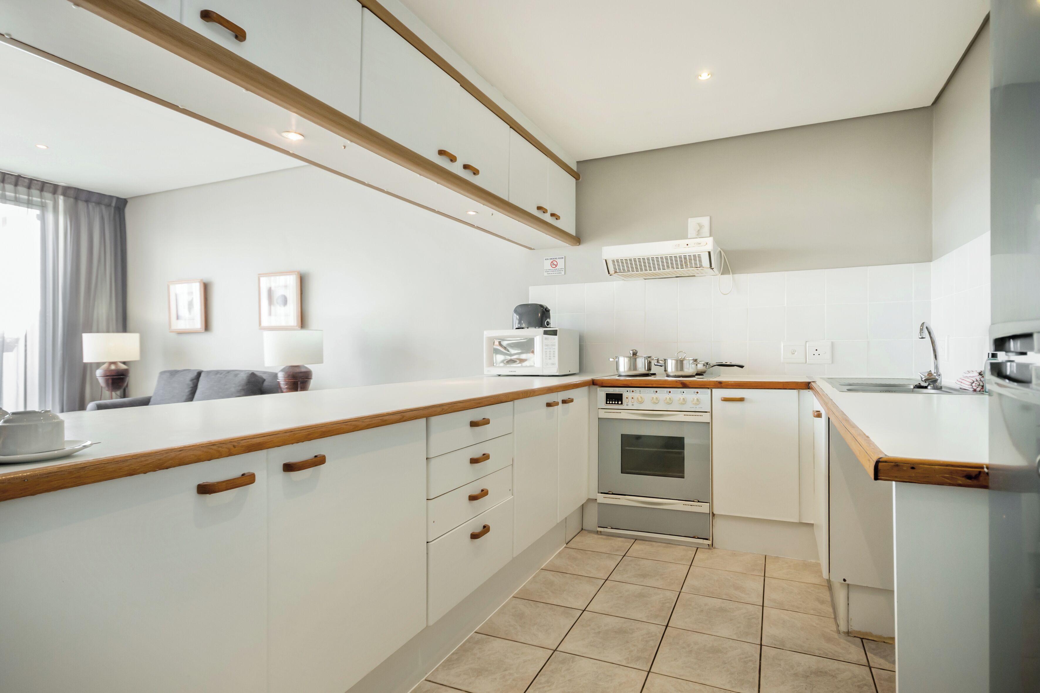 A modern kitchen with white cabinets, wooden countertops, a built-in oven, and a microwave.